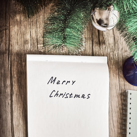 Merry Christmas is handwritten on the paper, and next to it is a Christmas tree with toysの写真素材