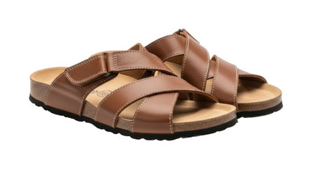 A pair of brown leather sandals with crisscross straps and cork soles are shown isolated on a white background.の素材