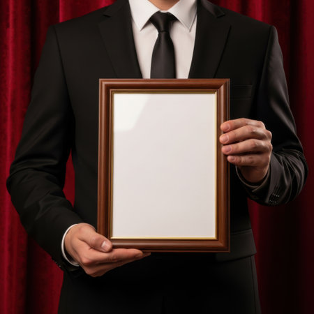 A formally dressed individual presents a blank wooden award frame, ready for personalization. The rich red curtain adds a dramatic and celebratory atmosphere, perfect for recognition events.の素材