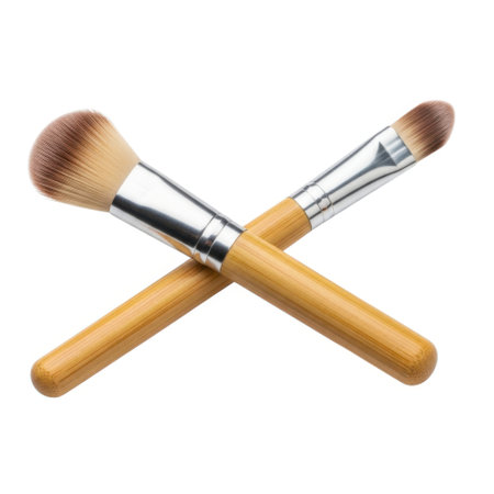 A detailed close-up captures two essential makeup brushes elegantly crossed. Their soft bristles and natural wooden handles suggest quality and precision for flawless beauty application.の素材