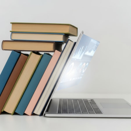 A collection of old books is arranged next to a contemporary laptop, all presented on a clean white background.の素材