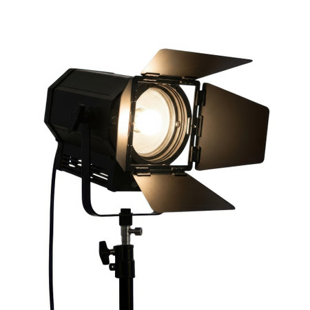 A professional black stage lighting fixture with barn doors is illuminated and isolated on a white background.の素材