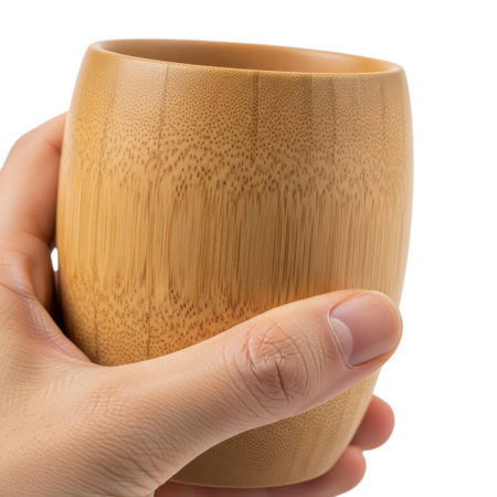 A close-up shot features a hand gently grasping a unique bamboo cup. The natural grain and warm tones of the sustainable material are prominently displayed, highlighting its organic beauty and eco-friendly appeal.の素材