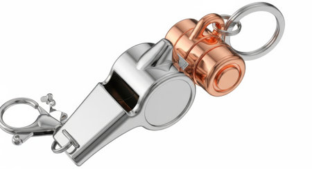 A shiny metal whistle and a copper capsule are attached to a keychain, presented isolated on a white background.の素材