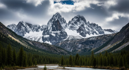 Majestic snow-covered mountain peaks dominate the background, framed by a dense evergreen forest and a winding river in the foreground.の素材