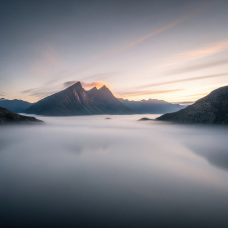 A serene panorama of mountains emerging from a dense fog blanket during a vibrant sunrise, casting warm hues across the sky.の素材