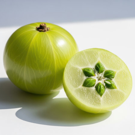 A whole amla fruit sits beside a halved amla, showcasing its unique star-shaped seed structure.の素材