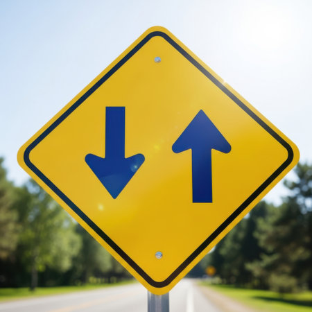 A bright yellow diamond traffic sign displays two opposing blue arrows, signifying a two way road ahead.の素材