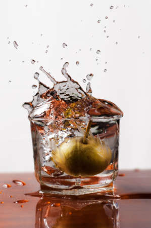 Water splash into a glass with a decorative pear の写真素材