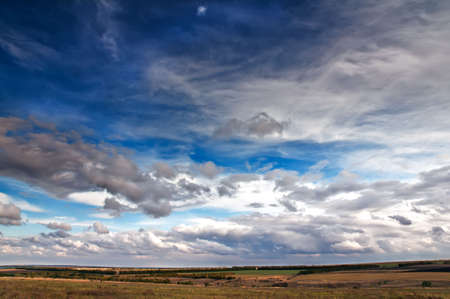 Cumulus clouds are over hilly fields in clear dayの写真素材