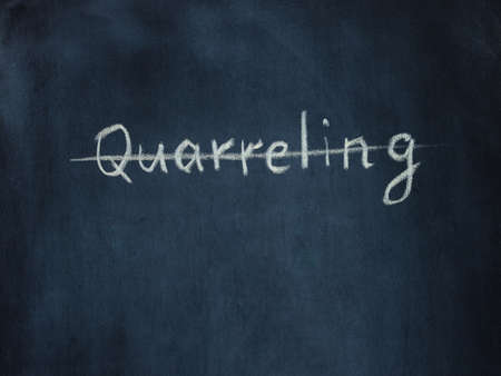 crossed out the word Quarreling on black chalkboard. Psychology concept