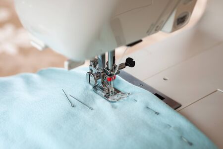 Part sewing machine with twin needle, blue fabric and pins