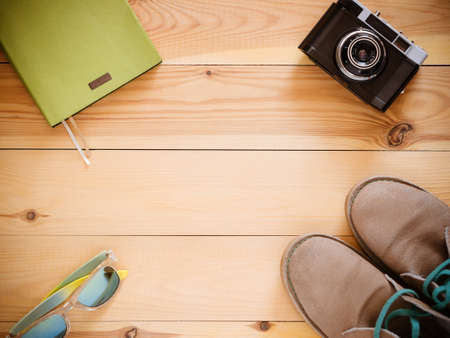 Set of travel and resort stuff. Old 35mm camera, note book, sunglasses and desert boots on wooden table. Top view, flat lay with copy spaceの写真素材