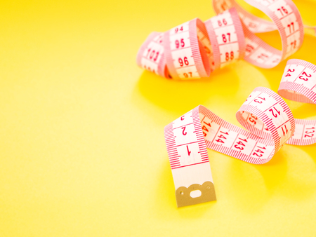 Red and white measuring tape on yellow background