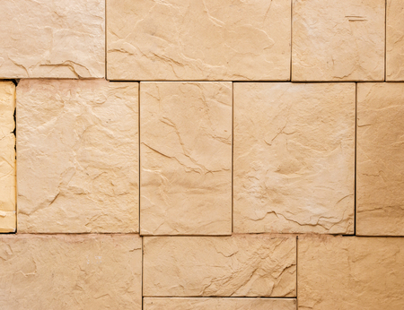 a wall from an artificial beige stone facade with rough fractured surfacesの写真素材