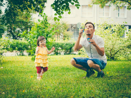 Dad and his daughter are making bubbles in the park. Colorful image for modern lifestyle family conceptの写真素材