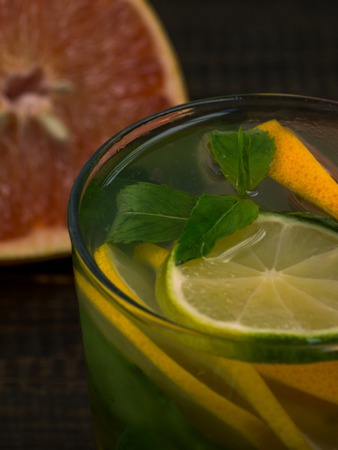 Close up cold homemade lemonade with fresh lemon, lime, grapefruit and mint. Summer drink on dark...