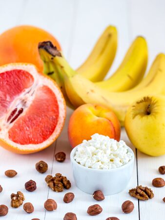 Healthy breakfast: cottage cheese, fruits and nuts on white wooden background. Dieting, healthy lifestyle concept meal. Verticalの写真素材