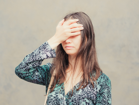 facepalm girl. Portrait of young woman doing facepalm posing against gray wall backgroundの写真素材