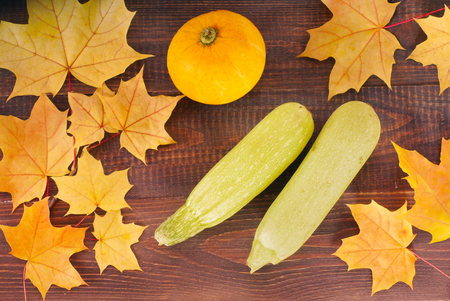 Pumpkin and zucchini on wooden table with autumn leaves. Flat lay or top view. Food and drink, holidays, halloween conceptの写真素材