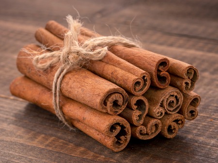 Ground cinnamon, cinnamon sticks, tied with jute rope on wooden background. Close upの写真素材