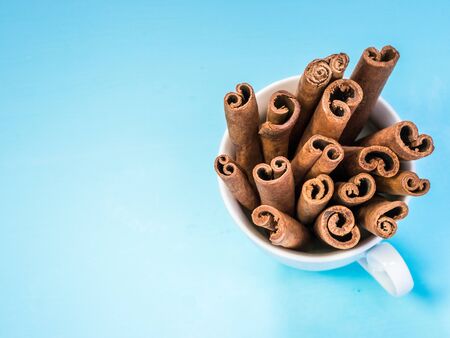 Ground cinnamon, cinnamon sticks on blue background with copy space. Flat lay or top view