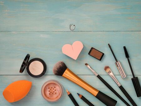 Set of make up on turquoise wooden background. Mascara brush, eyebrow gel brush, pencil, eyeshadow, sponge and brushes. Mock up with copyspace. Shallow DOFの写真素材