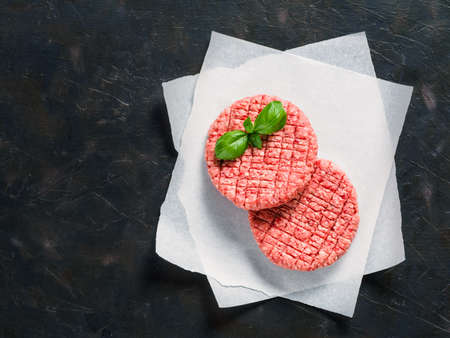 Two raw beef meat steak cutlets for burger on black concrete background with copy space. Making homemade burger concept. Top view or flat lay.の写真素材