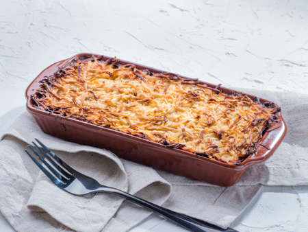 Close up view of appetizing potato casserole with fish, eggs and cream. Potato casserole in serving baking dish on white concrete backgroundの写真素材