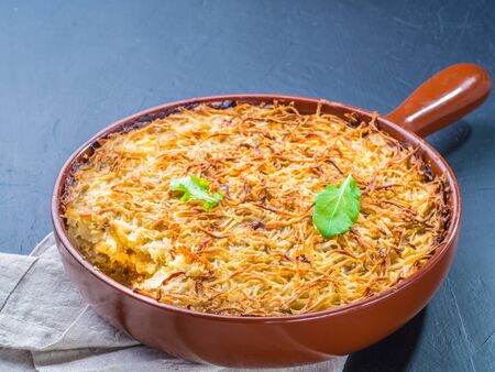 Close up view of appetizing potato casserole with fish, eggs and cream. Potato casserole in serving baking pan on dark concrete backgroundの写真素材