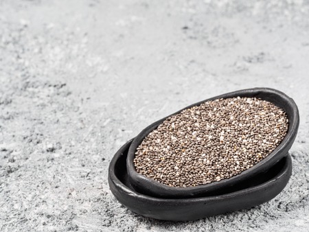 Close up view of chia seeds in trendy plate with copy space. Chia seed on gray concrete textured background. Healthy food and diet conceptの写真素材