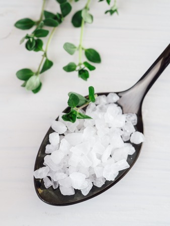coarse sea salt in black spoon with thymeの写真素材