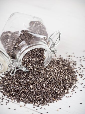 chia seeds scattered from glass jar on white backgroundの写真素材