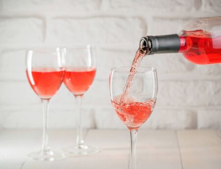 Pouring pink wine from bottle into wineglassの写真素材