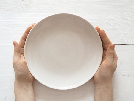 Female hands and empty plate isolated on whiteの写真素材