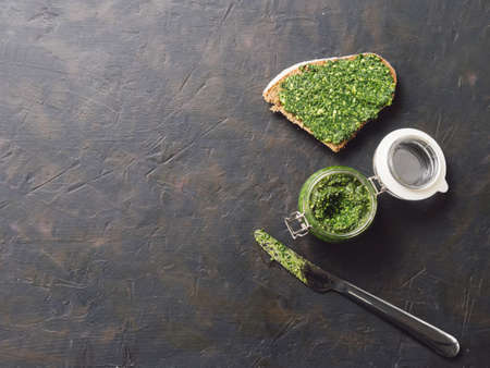 Whole grain rye bread with fresh basil pesto sauce on dark concrete background. Top view or flat-lay. Copy space.の写真素材