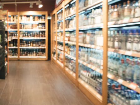 Blurred supermarket with alcohol bottles on shelves - background with shallow DOF. Copy space.の写真素材