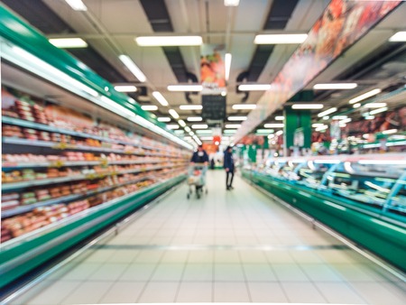 Abstract blurred supermarket aisle with colorful shelves and unrecognizable customers as backgroundの写真素材