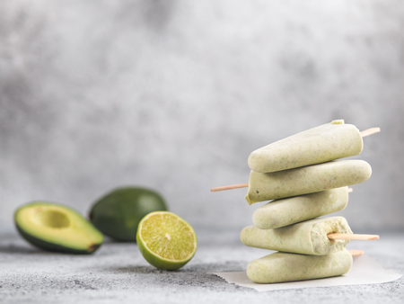Homemade raw vegan avocado lime ice cream. Sugar-free, non-dairy green ice cream on gray cement textured background. Copy space. Ideas and recipes for healthy snack, dessert or smoothieの写真素材