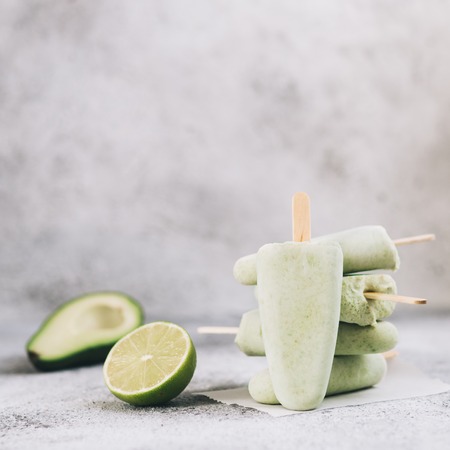 Homemade raw vegan avocado lime popsicle. Sugar-free, non-dairy green ice cream on gray cement textured background. Copy space. Ideas and recipes for healthy snack, dessert or smoothieの写真素材