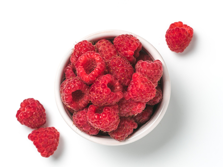 View from above of ripe raspberry in small bowl on white background. Organic raspberries isolated on...
