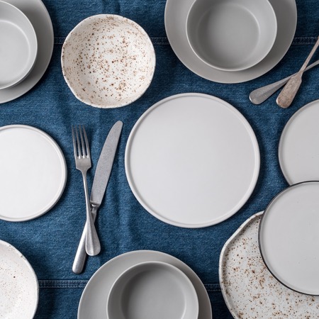Empty ceramic tableware. Ceramic plates on jeans tablecloth or runner. Overview empty food table...