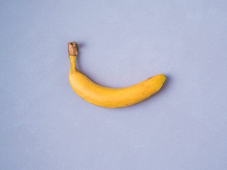 One banana on violet lavener colour background. Creative layer of banana. Single ripe banana fruit...