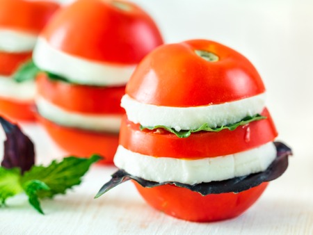 Ready-to-eat fun layered appetiezer with tomatoes,cheese, purple basil,mint leaf. Ideas and recipes for healthy breakfast, dinner, appetiezer, salad.Can use for design cheese dairy.Copy space for textの写真素材