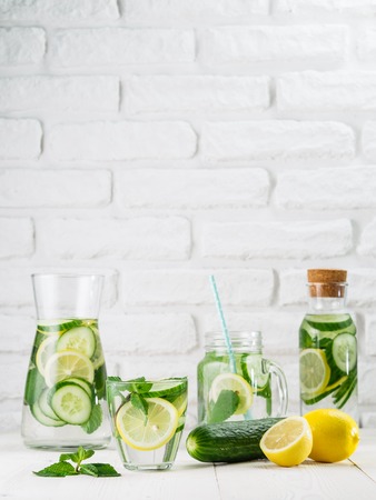 Infused detox water with cucumber, lemon and mint in different glass bottles on white table. Diet, healthy eating, weight loss concept. Copy spaceの写真素材
