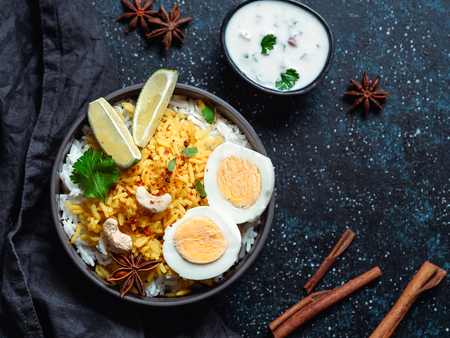 Indian Egg Biryani or anda rice top view on dark background. Egg Biryani - Basmati rice cooked with masala roasted eggs and spices, served with yogurt. Copy space for textの写真素材