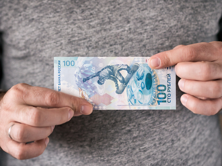 Hands hold russian rubles. Anniversary banknote of one hundred russian rubles in men's hands.. Selective focus. Shallow DOFの写真素材