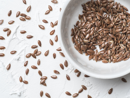 Flax seeds with copy space. Brown flax seed on white concrete textured background. Top view or flat lay. Copy space. Healthy food and diet conceptの写真素材
