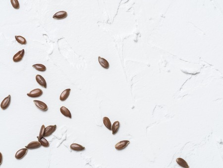Flax seeds with copy space. Brown flax seed on white concrete textured background. Top view or flat lay. Copy space. Healthy food and diet conceptの写真素材