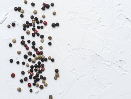 Assorted peppercorns. Medley trio colorful peppercorn on white textured concrete background with copy space. Top view or flat lay.の写真素材